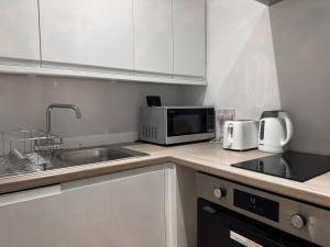 a kitchen with a sink and a microwave at Central Hub For Maidstone, Cosy Suite Book Now in Maidstone