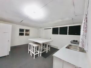 a white kitchen with a sink and a table at Tonga Airport Cottage - Entire Place in Fua‘amotu