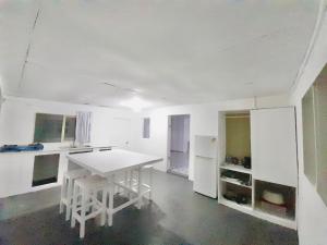 a white kitchen with a table and a refrigerator at Tonga Airport Cottage - Entire Place in Fua‘amotu