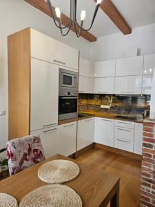 a kitchen with white cabinets and a wooden table at Arina Guest Apartment in Kuressaare