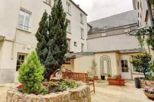 a garden in front of a building with a pine tree at Le Courcillon Calme, Cour privée & Proche Château in Versailles