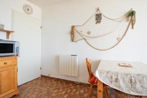 a kitchen with a table and a clock on the wall at Appartement face à la mer in La Grande-Motte