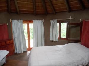a bedroom with a white bed and two windows at Tierra Colibrí in Punta Colorada