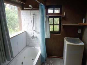 a bathroom with a tub and a shower with a window at Tierra Colibrí in Punta Colorada