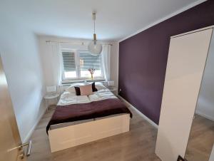 ein Schlafzimmer mit einem Bett und einer lila Wand in der Unterkunft Reiseglück in Künzell