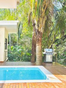 an outdoor swimming pool with a tree and a grill at Cosmos House in the Jungle in Santa Teresa Beach