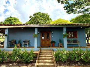 a blue house with a wooden door and stairs at Sítio Santo Antônio in Piracicaba