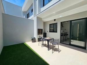 een patio met een tafel en stoelen en een groen tapijt bij Sobrado novíssimo 3 quartos melhor bairro de foz in Foz do Iguaçu