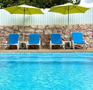 three chairs and umbrellas next to a swimming pool at Hakuna Matata in Cano