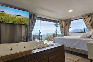 a bedroom with a tub and a bed and a tv at Recanto Pôr do Sol com Hido e lareira in Santo Amaro da Imperatriz