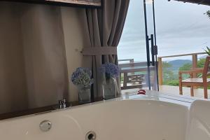 a bath tub with flowers in a bathroom with a balcony at Recanto Pôr do Sol com Hido e lareira in Santo Amaro da Imperatriz +34 photos