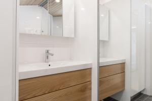 a white bathroom with a sink and a mirror at Glorious penthouse with private sauna and jacuzzi in Helsinki +39 photos