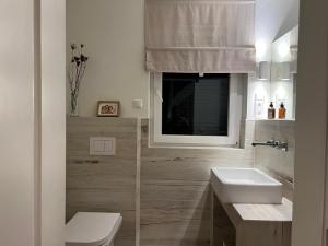 a bathroom with a sink and a toilet and a window at Häuschen mit privatem Schleizugang in Maasholm +8 photos
