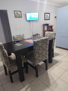a black table with chairs and a television in a room at Alojamiento temporario Bordon in San Salvador