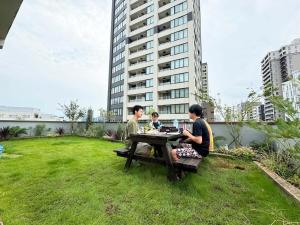 three people sitting at a picnic table in the grass at Time Camp 高輪 in Tokyo