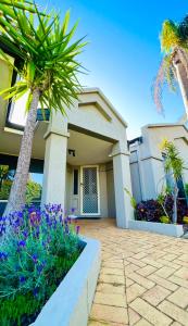 a house with palm trees and flowers in front of it at Beautiful home Queen bed near train station in Cockburn Central