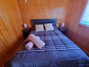 a bed in a room with two pillows on it at Cabaña Antü Küyen Melipeuco 02 in Melipeuco