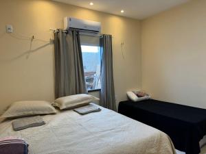 ein Schlafzimmer mit einem Bett mit zwei Kissen und einem Fenster in der Unterkunft Linda Casa Aconchegante Aquiraz in Aquiraz + 36 Fotos