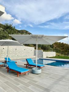 a pool with two blue chairs and a white umbrella at Villa Panorama - Private Swimming Pool & Parking in Sarandë