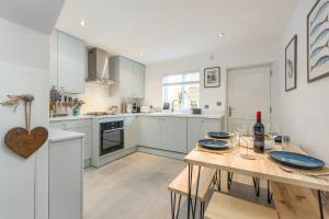 une cuisine avec des armoires blanches et une table en bois dans l'établissement Charming 2 Bed Cottage - within city walls - free parking- garden, à Canterbury