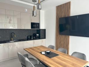 cocina con mesa con sillas y TV de pantalla plana en Apartament Lazur by Eleganckie Apartamenty Sianożęty - 100 metrów od plaży, wysoki standard, en Sianożęty