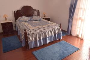 a bedroom with a bed with blue rugs on the floor at Quinta da Colina in São Vicente