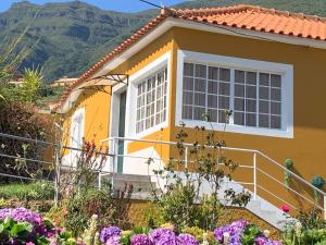 a yellow and white house with mountains in the background at Quinta da Colina in São Vicente