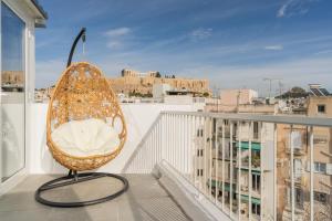 a rattan chair sitting on top of a balcony at The Minion Elegant Suite - Acropolis View in Athens