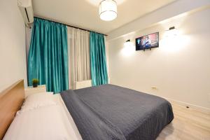 a bedroom with a bed and a television on the wall at CityScape Bucharest in Bucharest