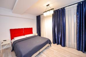 a bedroom with a red bed and blue curtains at CityScape Bucharest in Bucharest