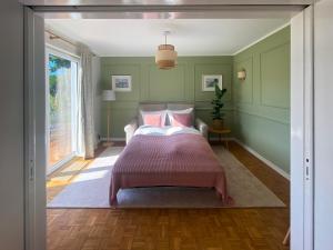 a bedroom with green walls and a bed with pink pillows at Lykke Hus - Traumhaus für bis zu 10 Personen in Timmendorfer Strand