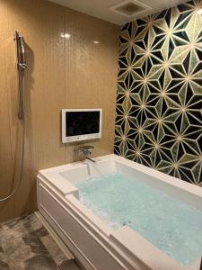 a bathroom with a tub with a tv on the wall at Dai Tokyo (Adult Only) in Takamatsu