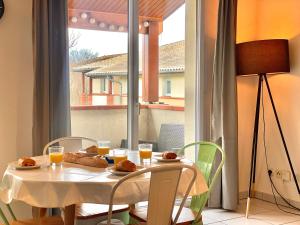 een witte tafel met eten en drinken en een raam bij " Côté Parc " Cité de l'espace - Entrée autonome in Toulouse