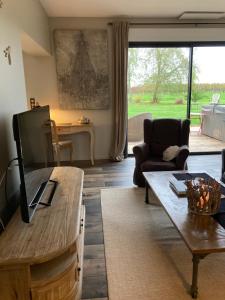 un salon avec une télévision et une table dans l'établissement La Longère de Chillac campagne chic jacuzzi, à Morizès