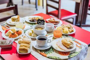 a table with plates of food and cups of coffee at VELINN Pousada Casa de Pedra Ilhabela in Ilhabela