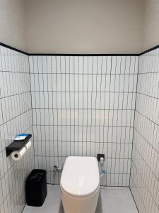 a bathroom with a toilet in a white tiled wall at Purple Stone High-End Designer Loft in Harbin