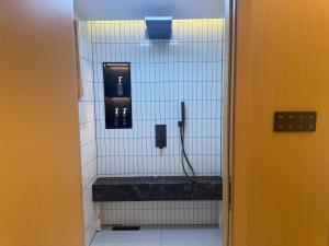 a bathroom with a shower with white tile walls at Purple Stone High-End Designer Loft in Harbin