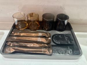 a tray with four bottles and four glasses on it at Purple Stone High-End Designer Loft in Harbin