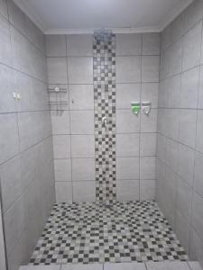 a bathroom with a shower with black and white tiles at Kudu Kottage in Phalaborwa