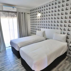 two beds in a hotel room with white sheets at Avrila Springs Hotel in Gaborone