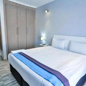a bedroom with a large white bed with a blue blanket at Avrila Springs Hotel in Gaborone