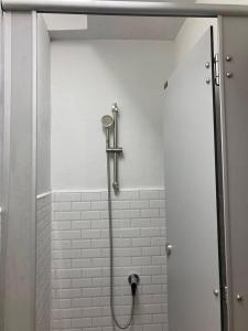 y baño con ducha y pared de azulejos blancos. en Best Stay 394 homestay, en Phra Khanong