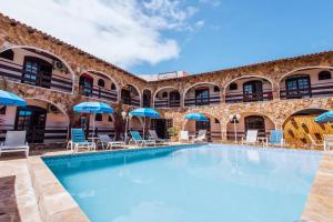 a pool with chairs and umbrellas in front of a building at VELINN Pousada Casa de Pedra Ilhabela in Ilhabela