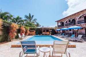 a swimming pool with chairs and a table and umbrellas at VELINN Pousada Casa de Pedra Ilhabela in Ilhabela