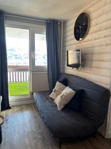 ein Wohnzimmer mit einem blauen Sofa und einer Uhr in der Unterkunft Appartement SUPERDEVOLUY in Le Dévoluy