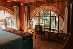 Hotel Boutique Finca La Niebla في كواتيبيك: غرفة نوم بها سرير وكرسي ونوافذ