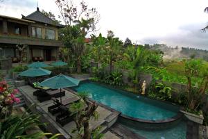 um resort com uma piscina com guarda-sóis em De Munut Balinese Resort em Ubud