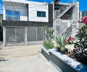 a white house with a gate and some flowers at Apartamento en Taganga in Taganga
