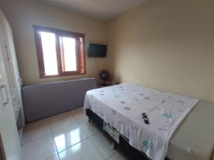 トラマンダイにあるCasa em Tramandaí perto do mar com pátio grandeのベッドルーム1室(ベッド1台、窓、バスタブ付)