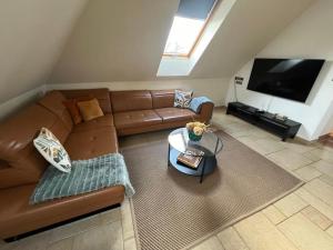 a living room with a brown leather couch and a flat screen tv at Maya Apartman in Szeged